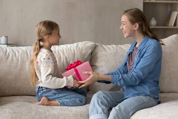 Jovem mãe alegre dando presente à pequena filha. — Fotografia de Stock