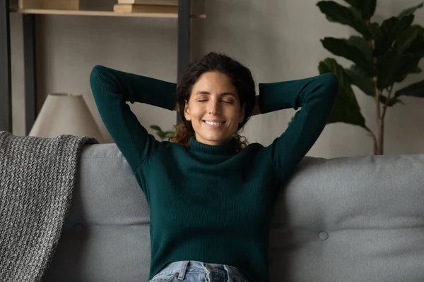 Gülümseyen genç Latin kadın kanepenin arkasında dinleniyor. — Stok fotoğraf