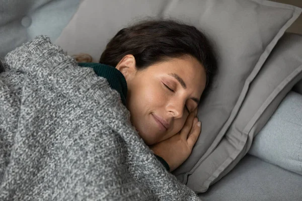 Kaygısız Latin kadın kanepede uyur ellerini yanaklarının altına koyar — Stok fotoğraf