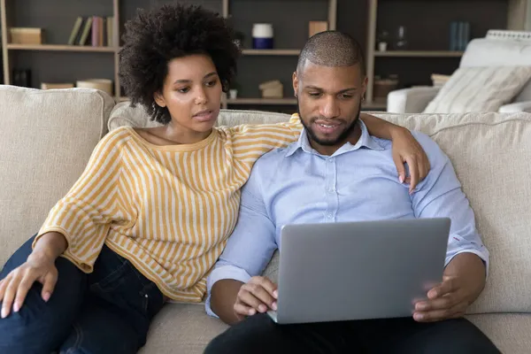 Joven pareja afroamericana usando computadora portátil en los hogares —  Fotos de Stock