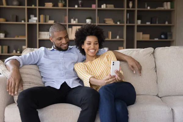 Alegre millennial negro pareja utilizando el teléfono móvil —  Fotos de Stock