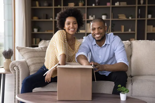 Feliz pareja africana joven emocionada recibiendo paquete —  Fotos de Stock