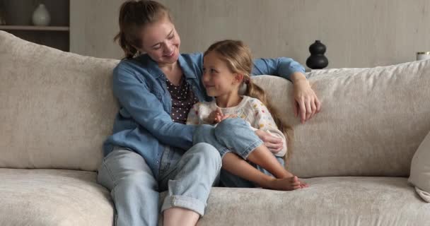 Mère adoptive aimante et fille adoptive préadolescente câlin sur le canapé — Video