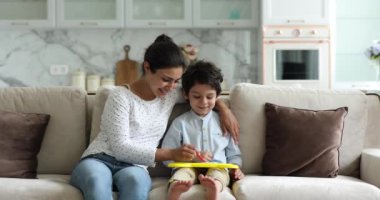 Hintli anne küçük oğlu için tahta üzerine resimler çiziyor.