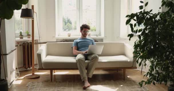 Young male relax on sofa read message on laptop screen — Stock Video