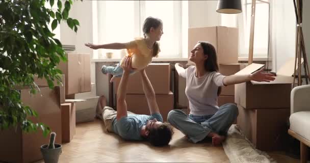 Захоплена сімейна пара грає з маленькою донькою в новій квартирі — стокове відео