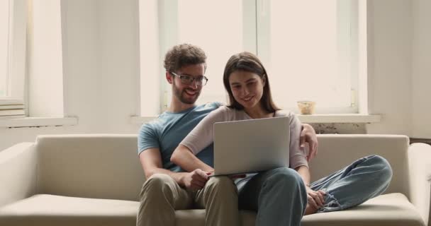 Millennial paar in liefde knuffelen op bank praten gebruik laptop — Stockvideo