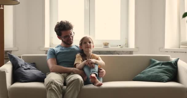 Feliz amoroso papai pequena filha abraçar no sofá conversa chat — Vídeo de Stock