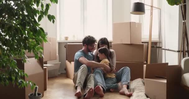 Ouders kleine dochter kietelen in de woonkamer op verhuizing dag — Stockvideo