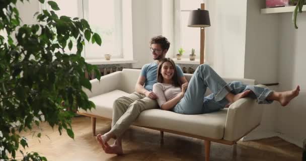 Pacífica jovem casal sereno abraçando no sofá acolhedor conversando sorrindo — Vídeo de Stock