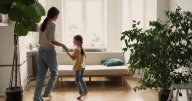 Genç kadın bebek bakıcısı küçük kıza evde dans etmeyi öğretiyor.