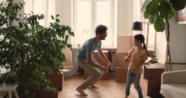 Baba, küçük kız, yeni ev sahipleri eşyaların arasında dans ediyor.