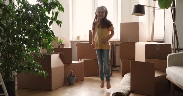 새 아파트 거실에서 뛰고 있는 기쁨에 찬 어린 소녀 — 비디오