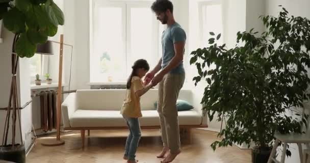Grappig papa klein meisje hand in hand springen in de woonkamer — Stockvideo