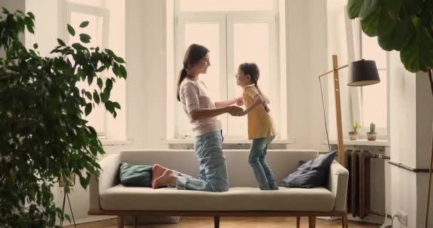 Moeder houden kleine dochter handen helpen bij het springen op de bank — Stockvideo