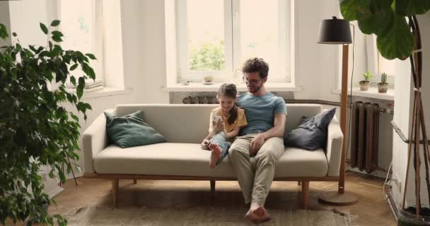 Jonge vader kleine dochter kijken grappige video op telefoon samen — Stockvideo
