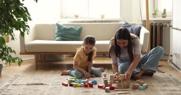 Giovane bambinaia giocare in legno costruttore insieme con la bambina in età prescolare — Video Stock