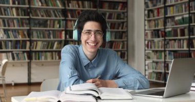 Üniversite kütüphanesinde öğrenci e-öğrencisiyim. Kameraya bakarak gülümsüyorum.