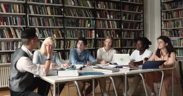 Sex tonårsstudenter med flera raser som studerar vid bordet i biblioteket — Stockvideo