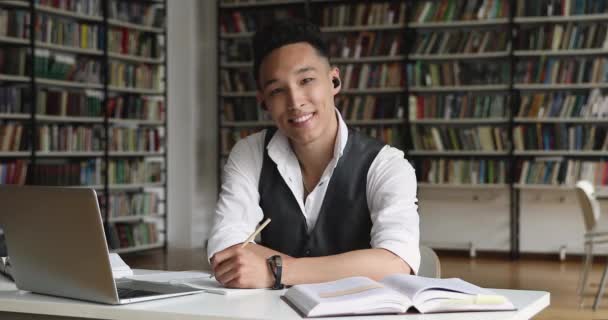 Hermoso asiático estudiante universitario sentarse en la biblioteca estudiando uso portátil — Vídeos de Stock