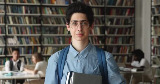 Sorrindo 16s estudante do ensino médio segurando livros posando na biblioteca — Vídeo de Stock