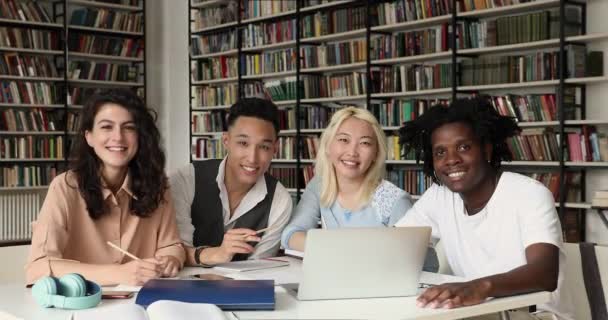 Estudiantes multiétnicos se sientan a la mesa en la biblioteca mostrando pulgares arriba — Vídeos de Stock