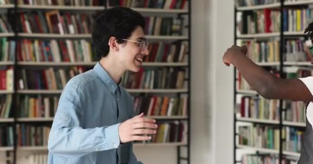 Studenten handdruk knuffelen terwijl ontmoeten elkaar in de universiteitsbibliotheek — Stockvideo