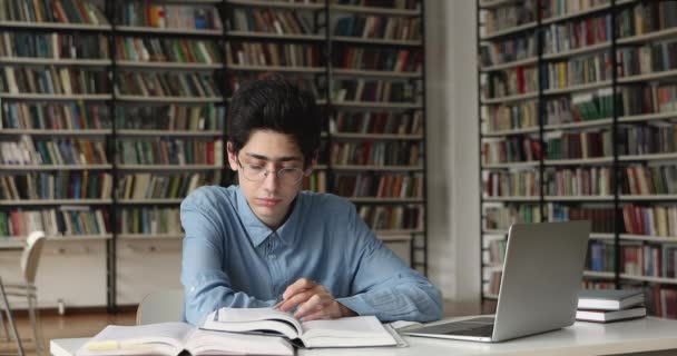 Colegial prepararse para los exámenes sentarse en el escritorio en la biblioteca — Vídeo de stock