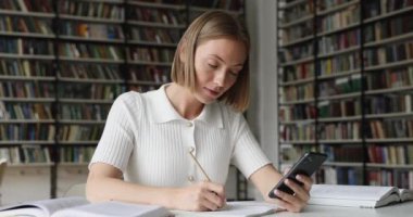 Öğrenci kız cep telefonu bilgilerini not defterinde tutuyor.