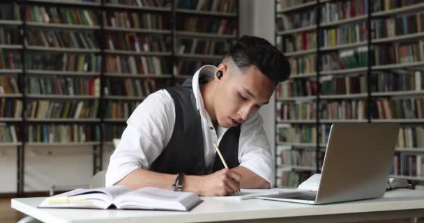 Азиатский студент учится через видео-звонок слушать репетитора написания заметок — стоковое видео