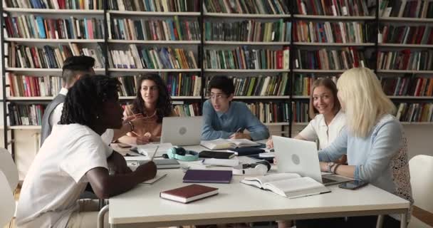 Πολυπολιτισμική ομάδα φοιτητών που σπουδάζουν κάθονται στο τραπέζι της βιβλιοθήκης — Αρχείο Βίντεο