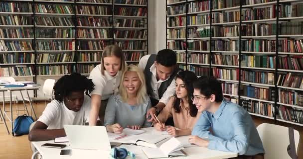 Mutlu üniversite öğrencileri kütüphanede oturup beşlik çakıyor. — Stok video