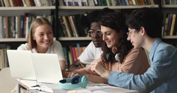 Diversos estudantes universitários sentam-se à mesa com laptop na biblioteca — Vídeo de Stock