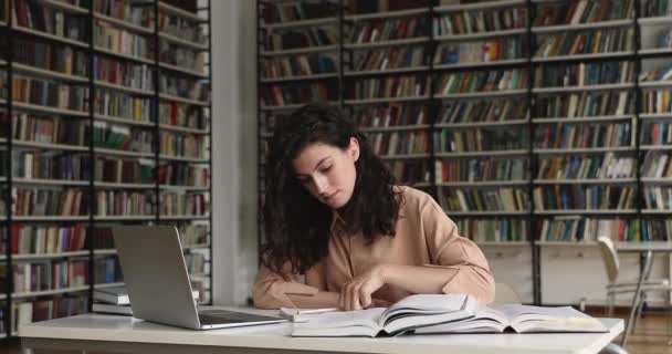 Estudiante prepararse para la prueba de escritura en copybook sentarse en la biblioteca — Vídeo de stock