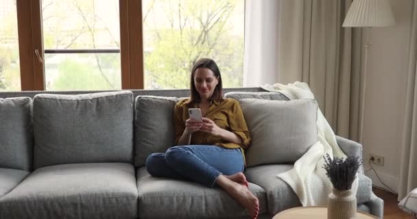 Teenager ruht auf Sofa und vernetzt sich mit Freund per Smartphone — Stockvideo