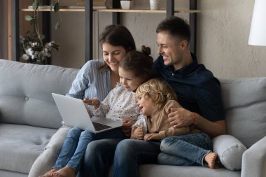 Mutlu anne ve baba dizüstü bilgisayarda online kitap okuyor.