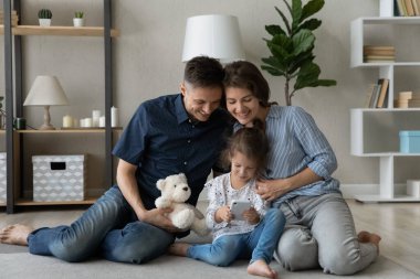 Mutlu ebeveynler tatlı kızları kucaklıyor, akıllı telefon kullanan çocukları izliyorlar.