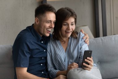 Mutlu şoke olmuş milenyum çifti akıllı telefon ekranına bakıyor.