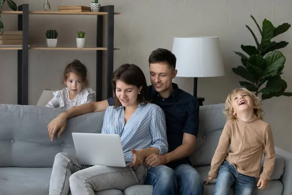 Happy rodiče relaxaci na gauči, pomocí online aplikace na notebooku — Stock fotografie