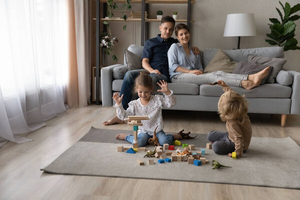 Happy cheerful sibling children playing with building blocks