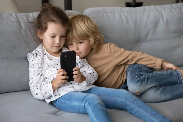 Lindos niños comprometidos en el juego de aprendizaje en línea en el teléfono inteligente — Foto de Stock