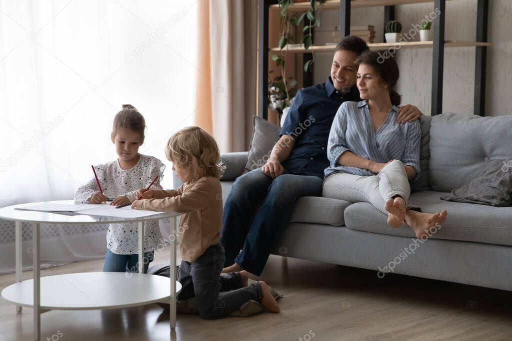 Relaxed happy millennial mom and dad resting on couch