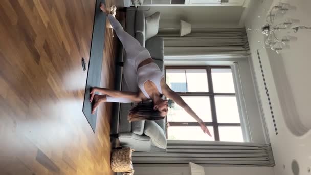 Sportieve slanke jonge vrouw doet yoga oefeningen thuis — Stockvideo