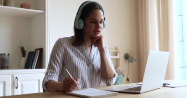 Kulaklıklı genç bir kadın dizüstü bilgisayar ekranından önce konuşur.