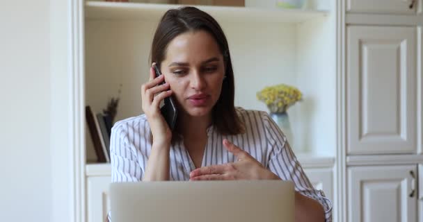 Mujer joven consultora experta cliente por computadora portátil en conversación telefónica — Vídeo de stock