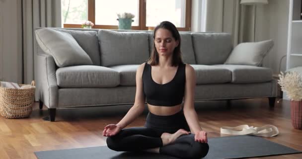 Milenyum bayanı evde yoga yapıyor. Nilüfer pozisyonunda meditasyon yapıyor. — Stok video