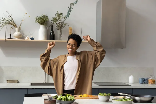 Fröhliche junge Afroamerikanerin tanzt, kocht in der Küche. — Stockfoto