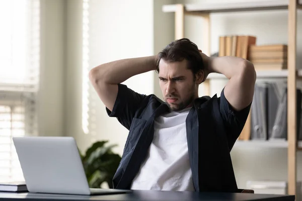 Frowning dissatisfied laptop user concerned, worried about problems