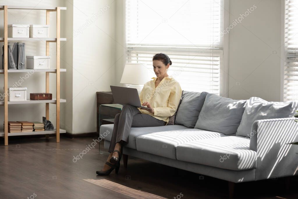 Middle aged business lady using laptop computer on couch