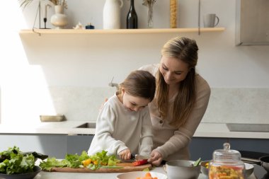 Küçük kızına yemek yapmayı öğreten mutlu bir anne..